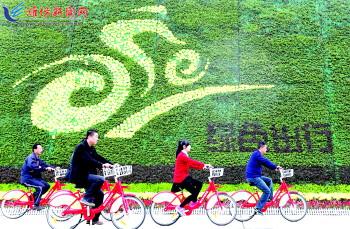 市民騎公共自行車路過市人民廣場一處花壇。記者 張馳